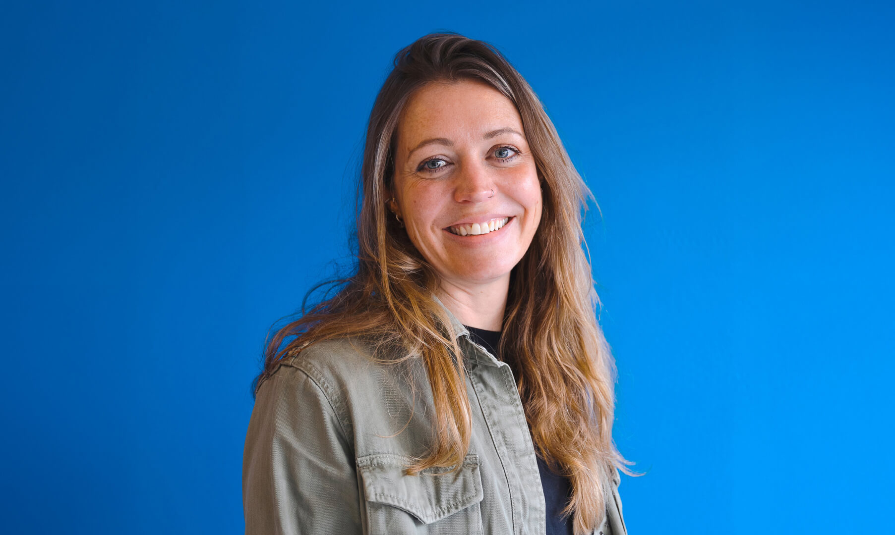Close up photo of Sarah, Halo's incredible Creative Director with a vibrant blue background.