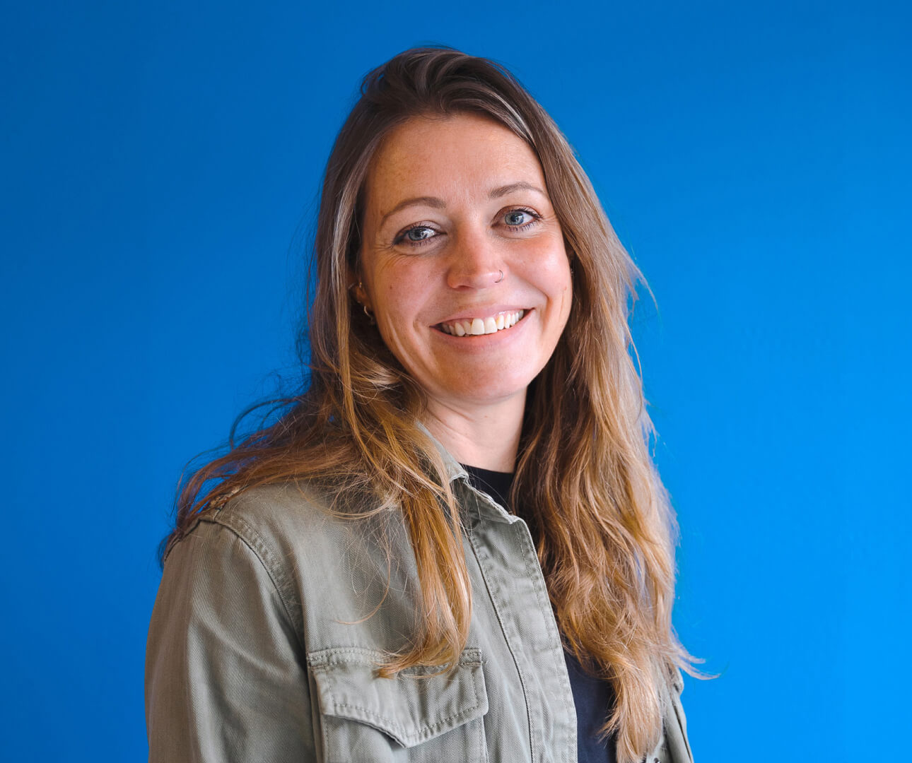 Close up photo of Sarah, Halo's incredible Creative Director with a vibrant blue background.