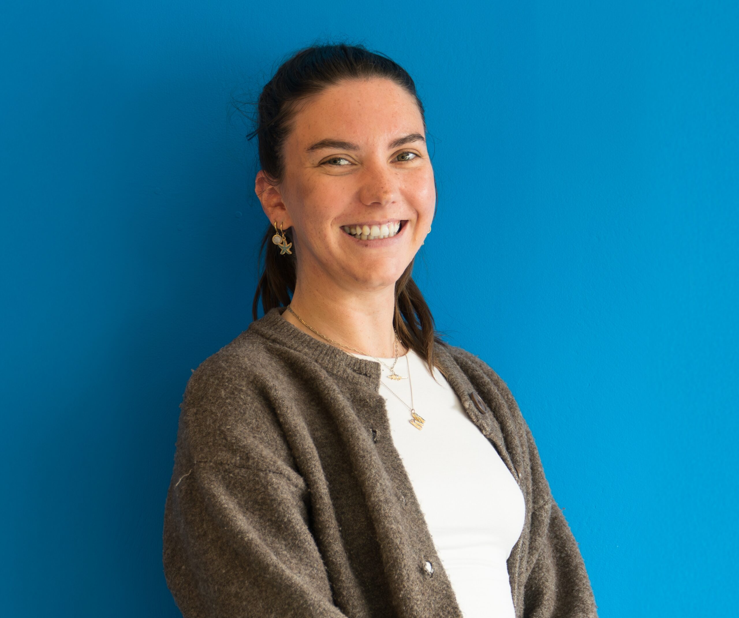 Image of Megan smiling in front of camera with blue background.