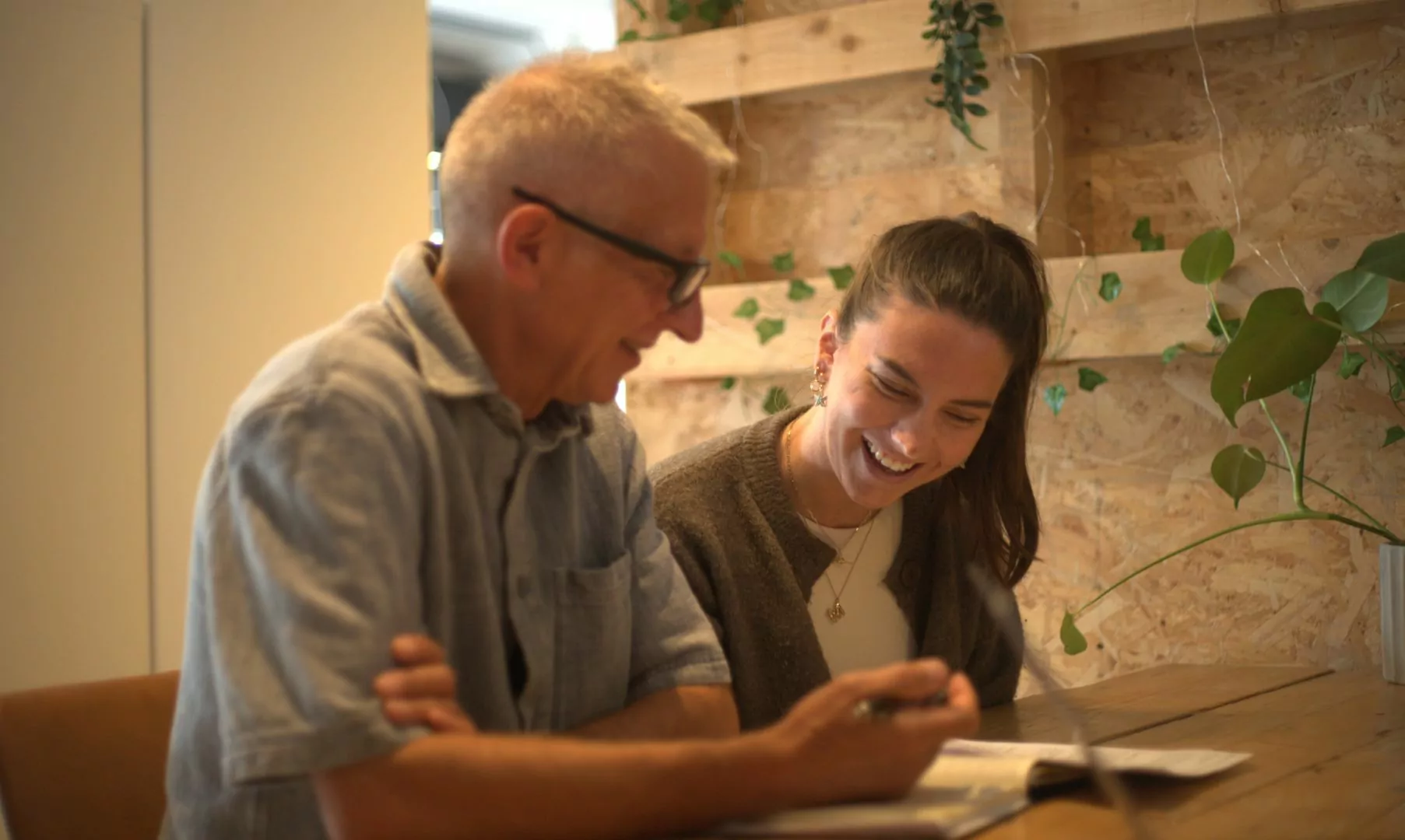Man and woman smiling whilst working together looking down at a piece of work.