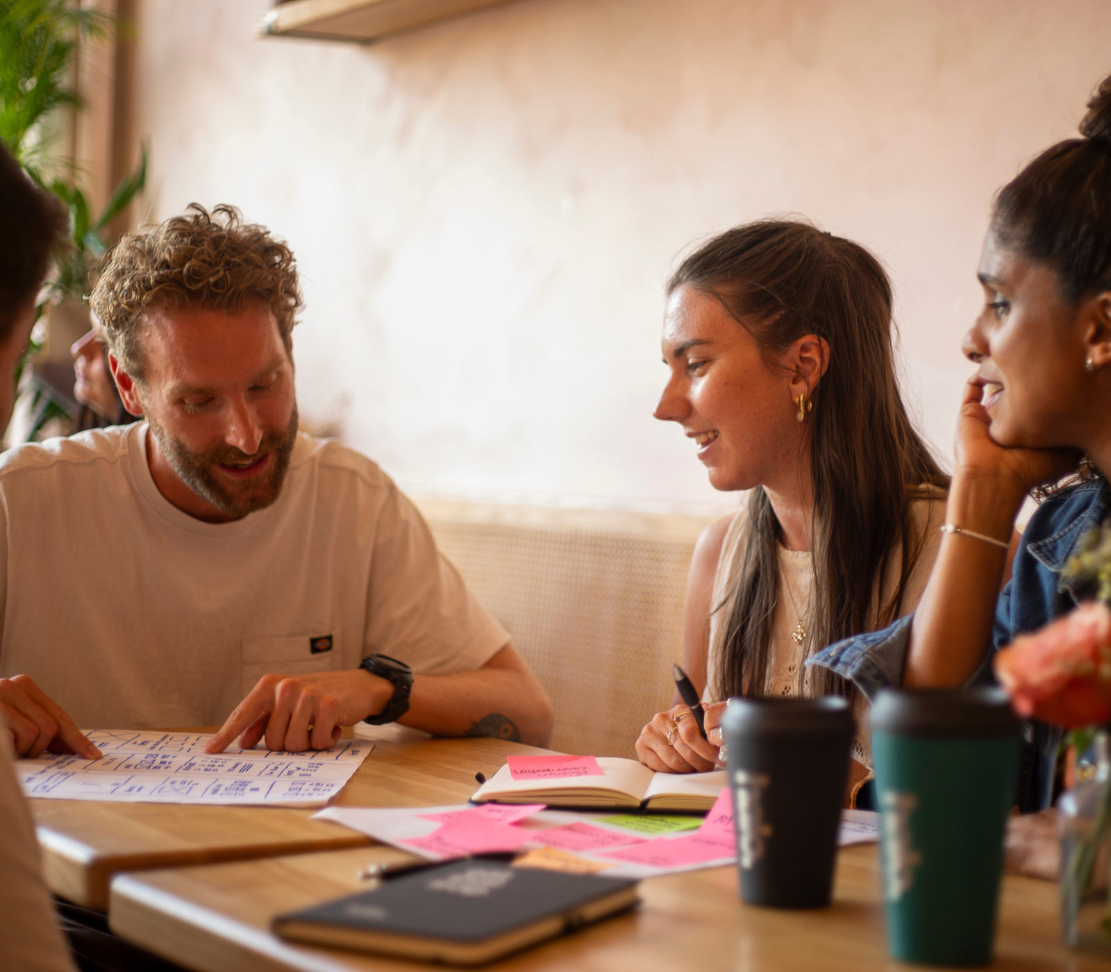 A diverse team of professionals actively collaborating around a wooden table, discussing documents, brainstorming ideas, and taking notes during a creative meeting, Halo Design Associates.